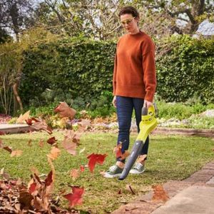 Souffleur 18V ONE+™ Ryobi - photo ambiance jeune femme soufflant des feuilles mortes dans un jardin