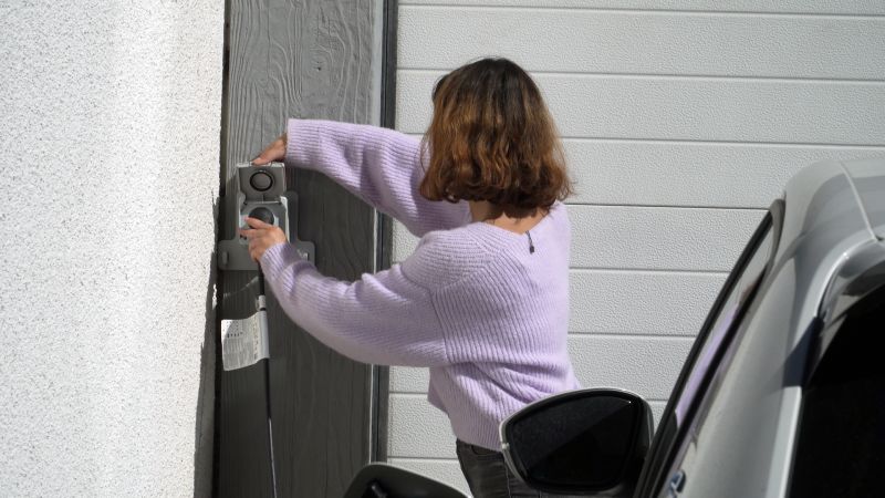 Photo d'une jeune femme branchant son véhicule électrique à la prise LEGRAND Green'up